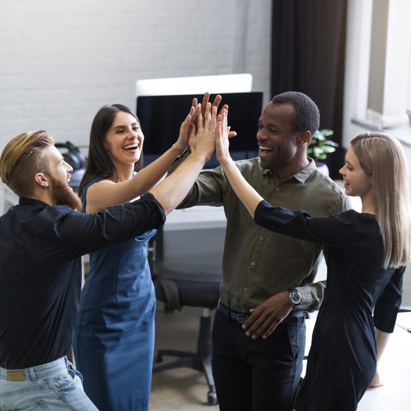 Group of young colleagues giving each other a high five